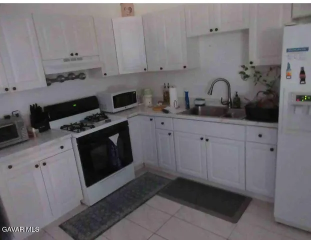 a kitchen with white cabinets and appliances