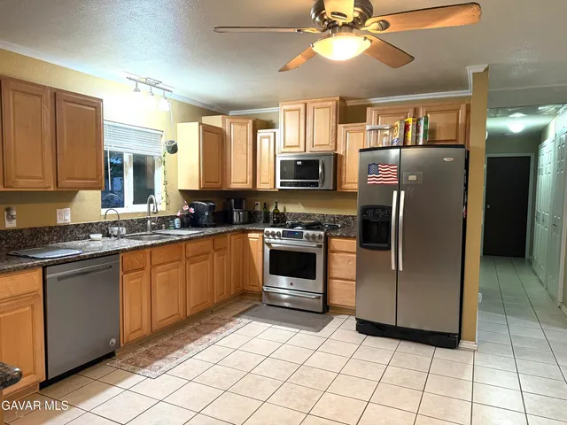 a kitchen with stainless steel appliances granite countertop a refrigerator a stove a sink and dishwasher a oven with white cabinets