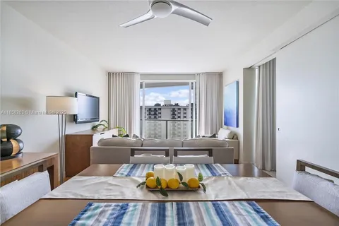 a living room with furniture a flat screen tv and a floor to ceiling window