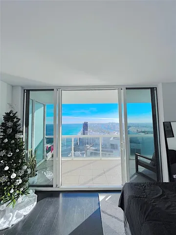 a living room with a balcony a bed and a potted plant