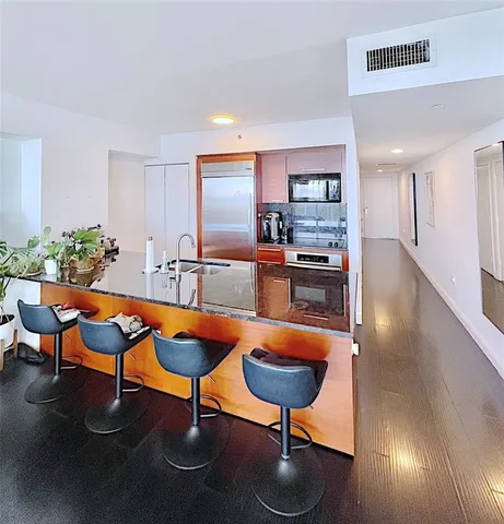 a kitchen with stainless steel appliances kitchen island granite countertop a table and chairs in it