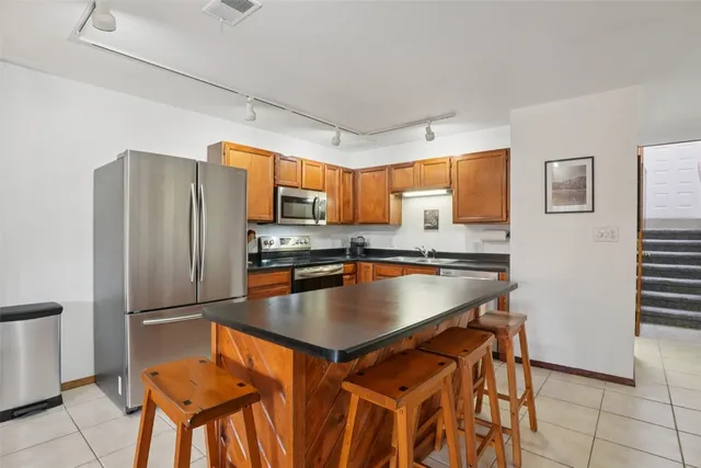 a kitchen with stainless steel appliances granite countertop a refrigerator a stove a sink a dining table and chairs