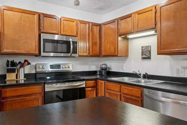 a kitchen with granite countertop a sink stainless steel appliances and cabinets
