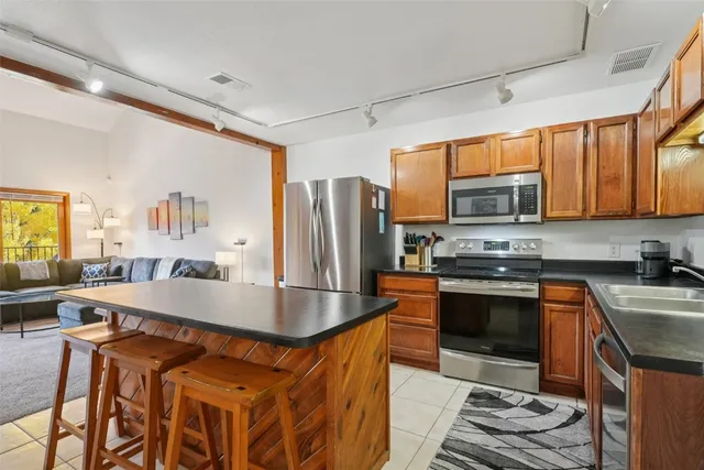 a kitchen with stainless steel appliances granite countertop a stove top oven a sink dishwasher a dining table and chairs with wooden floor