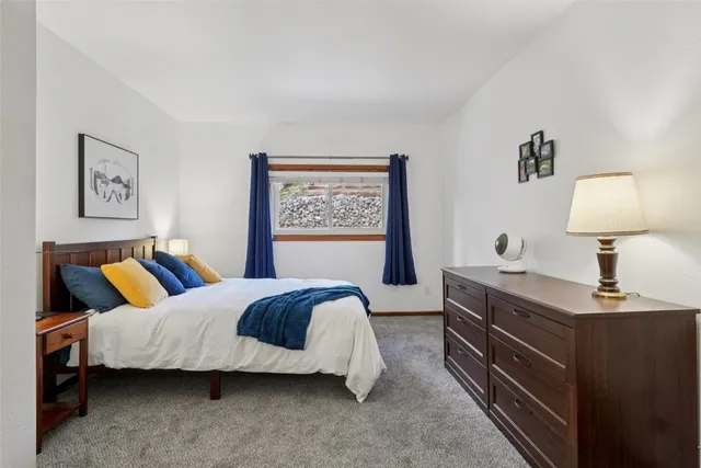 a bedroom with a bed and a lamp on dresser