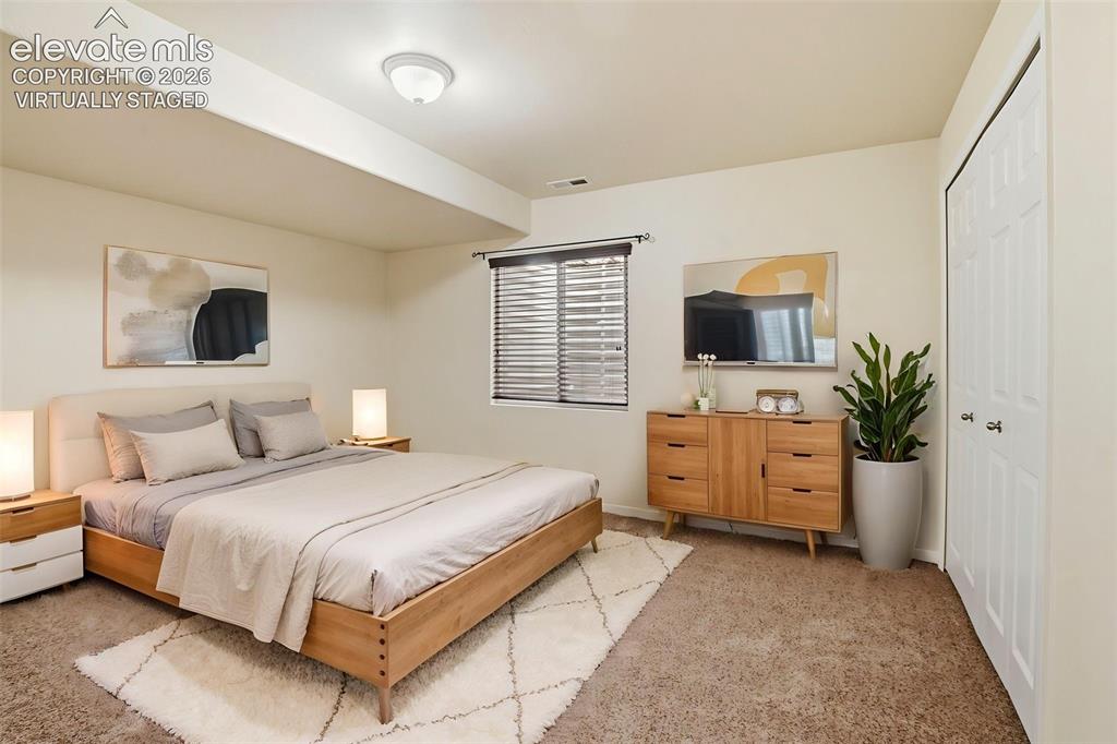 7806 Dutch Loop Colorado Springs, CO 80925 - Photo 26 of 41 a bedroom with a large bed and a flat tv screen on dresser