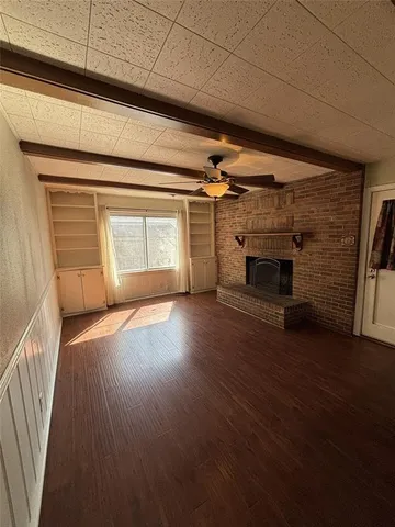 an empty room with wooden floor fireplace and windows