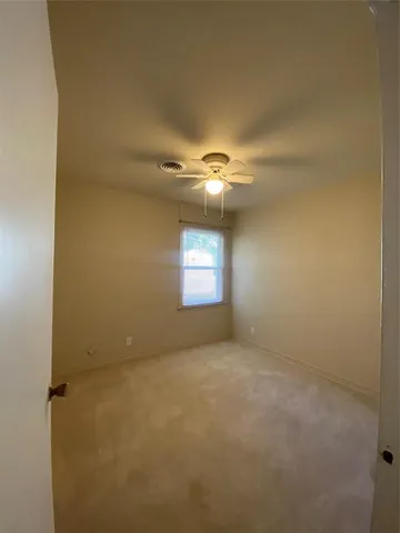 a view of an empty room and chandelier fan