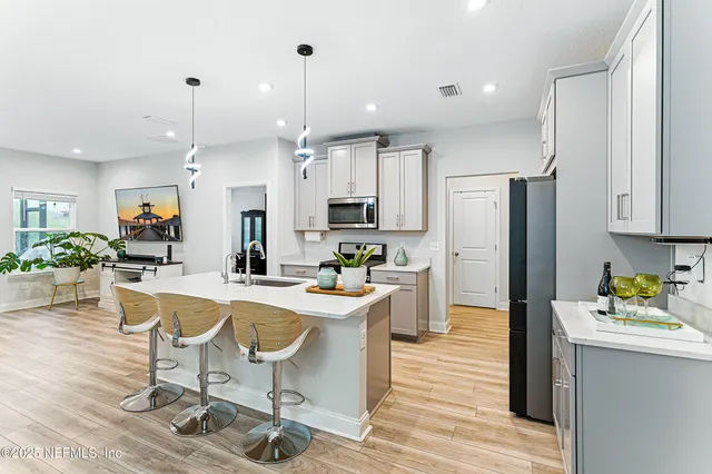 a kitchen with a refrigerator a stove a sink dishwasher a dining table and chairs with wooden floor