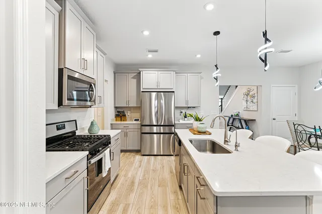 a kitchen with a sink a stove top oven a refrigerator cabinets and living room view