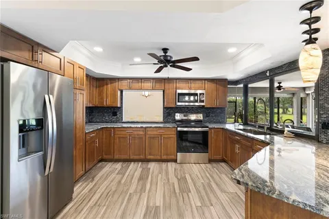 a kitchen with stainless steel appliances granite countertop a refrigerator a sink dishwasher a stove and white countertops with wooden floor