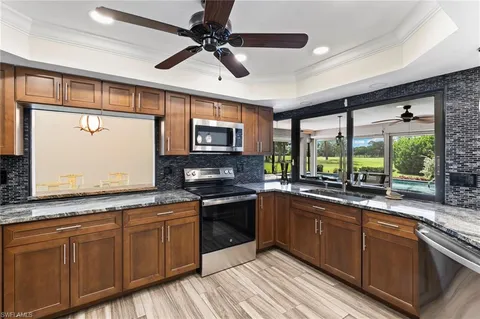 a kitchen with stainless steel appliances granite countertop refrigerator a sink a stove a microwave oven cabinets and wooden floor