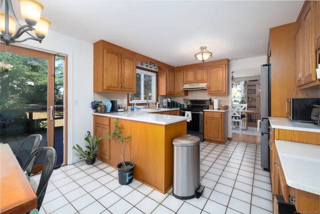 a kitchen with stainless steel appliances granite countertop a stove top oven a sink a dining table and chairs