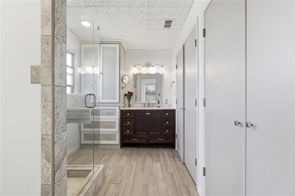 9213 Wilson Road Pilot Point, TX 76258 - Photo 16 of 36 Bathroom featuring a dark wood vanity with a light-toned countertop, a glass-enclosed shower, and wood-finish flooring