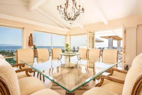 a view of a dining room with furniture a chandelier and large windows