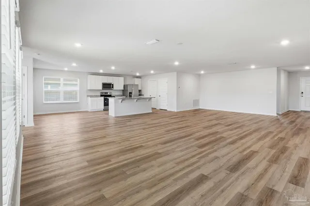 a kitchen with stainless steel appliances granite countertop a stove top oven a sink dishwasher and a refrigerator with wooden floor