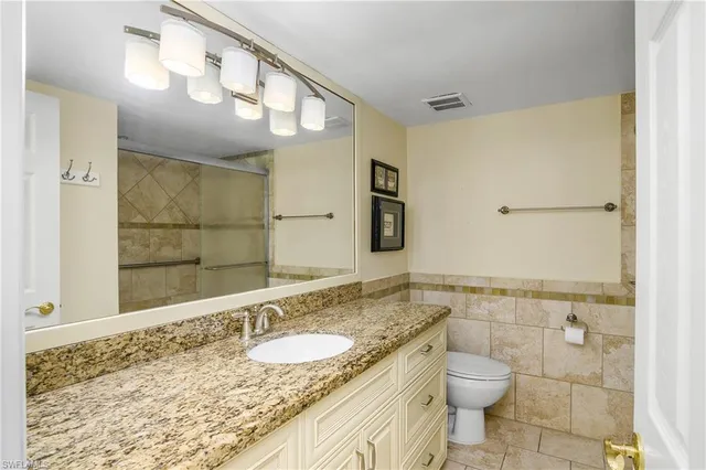 a bathroom with a granite countertop sink a mirror and a toilet