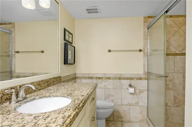 a bathroom with a granite countertop sink a mirror and a toilet