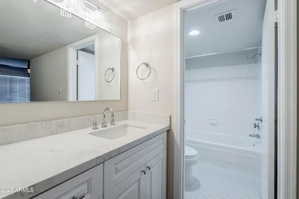 a bathroom with a granite countertop sink a toilet and shower