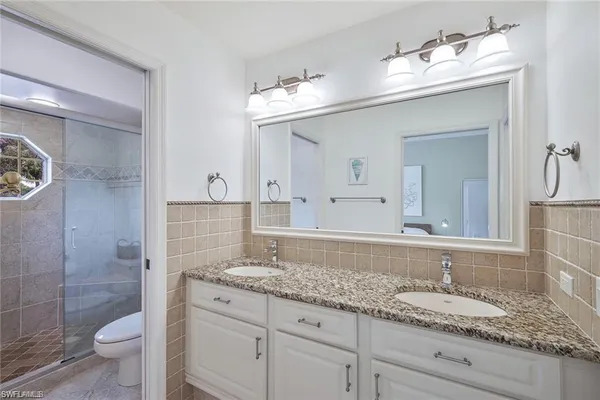 a bathroom with a granite countertop sink a toilet and a mirror