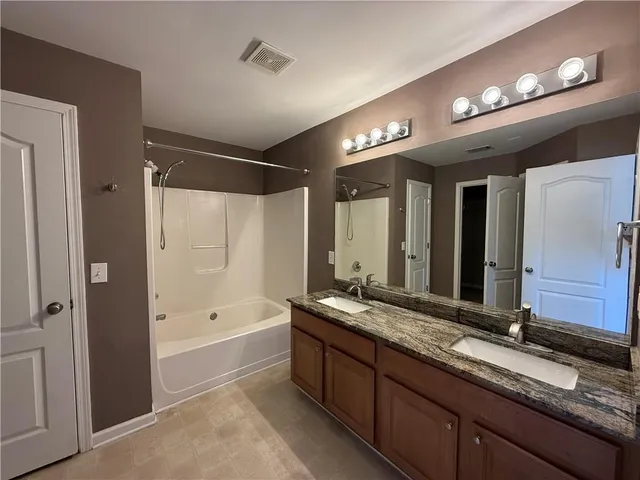 a bathroom with a tub a double vanity sink and a mirror