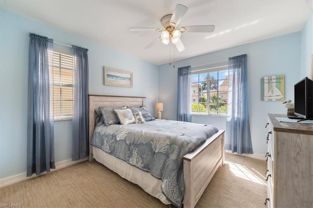 1715 Reuven Circle, Unit 2103 Naples, FL 34112 - Photo 20 of 38 a spacious bedroom with a bed a window and a flat screen television