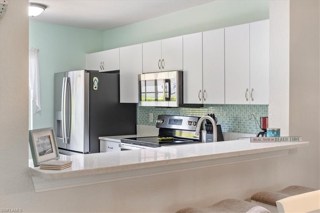 1715 Reuven Circle, Unit 2103 Naples, FL 34112 - Photo 25 of 38 Kitchen with appliances with stainless steel finishes, tasteful backsplash, white cabinetry, and light stone countertops