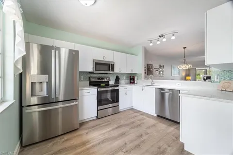 a kitchen with a refrigerator stainless steel appliances and white cabinets
