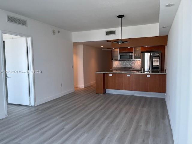 185 Southwest 7th Street, Unit 1403 Miami, FL 33130 - Photo 3 of 31 an empty room with wooden floor and kitchen view