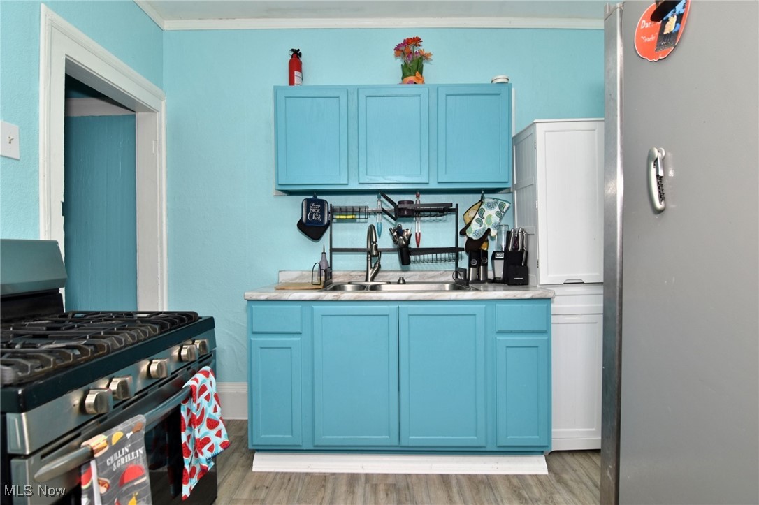 4213 Valley Road Cleveland, OH 44109 - Photo 27 of 47 Kitchen featuring light wood-style flooring, blue cabinetry, a sink, and gas stove
