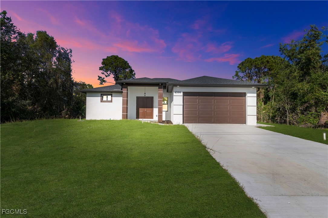 4306 2nd Street Southwest Lehigh Acres, FL 33976 - Photo 2 of 21 a front view of a house with a yard and garage