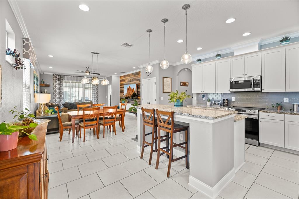 5196 Appenine Loop East St. Cloud, FL 34771 - Photo 4 of 39 a kitchen with stainless steel appliances kitchen island granite countertop a table chairs and a stove