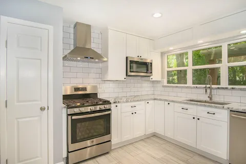 a kitchen with granite countertop a stove a sink and a microwave