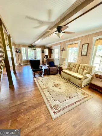 a living room with furniture hard wood floor and a large window