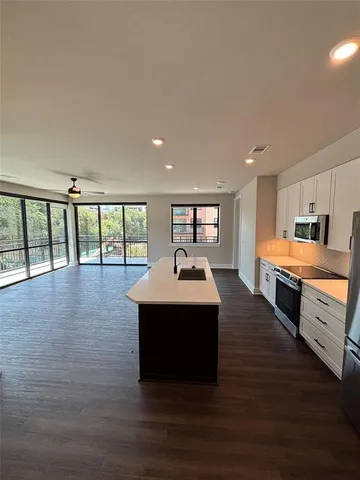 a large white kitchen with wooden floors and stainless steel appliances