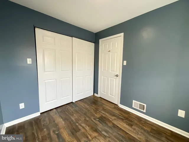 an empty room with wooden floor fireplace and windows
