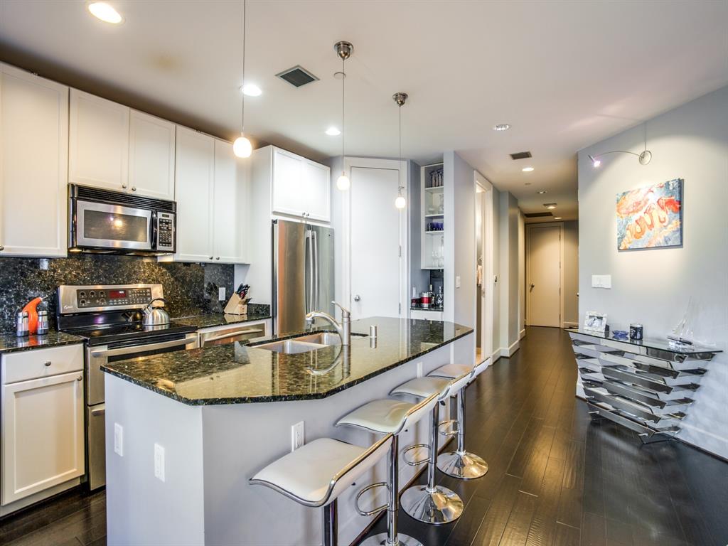a room with stainless steel appliances granite countertop a sink a stove and a refrigerator