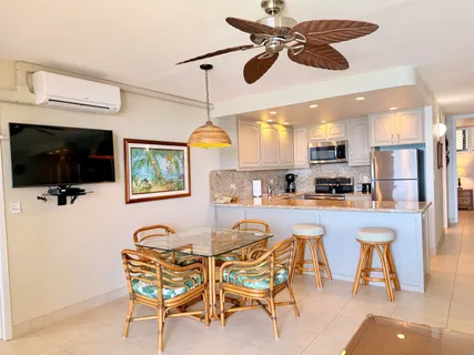 a kitchen with stainless steel appliances kitchen island granite countertop a dining table chairs refrigerator and sink
