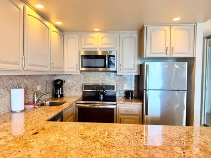 a kitchen with stainless steel appliances a stove a sink a microwave a refrigerator and cabinets