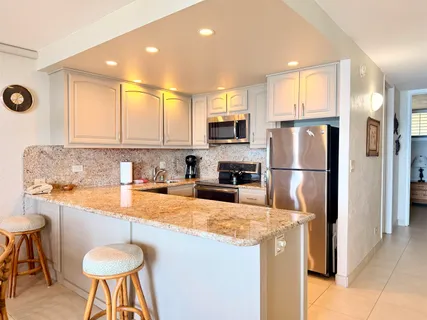 a kitchen with stainless steel appliances granite countertop a sink a stove a refrigerator cabinets and a dining table