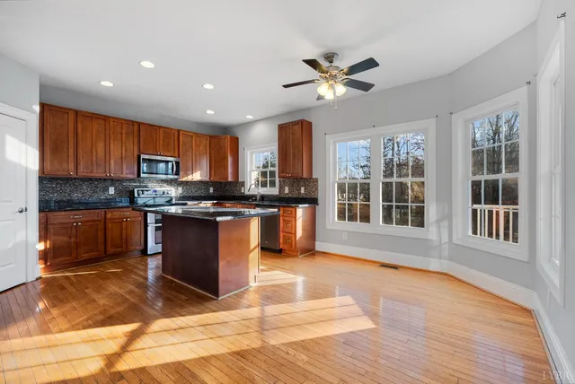 a large kitchen with stainless steel appliances granite countertop a refrigerator a stove a sink and a microwave