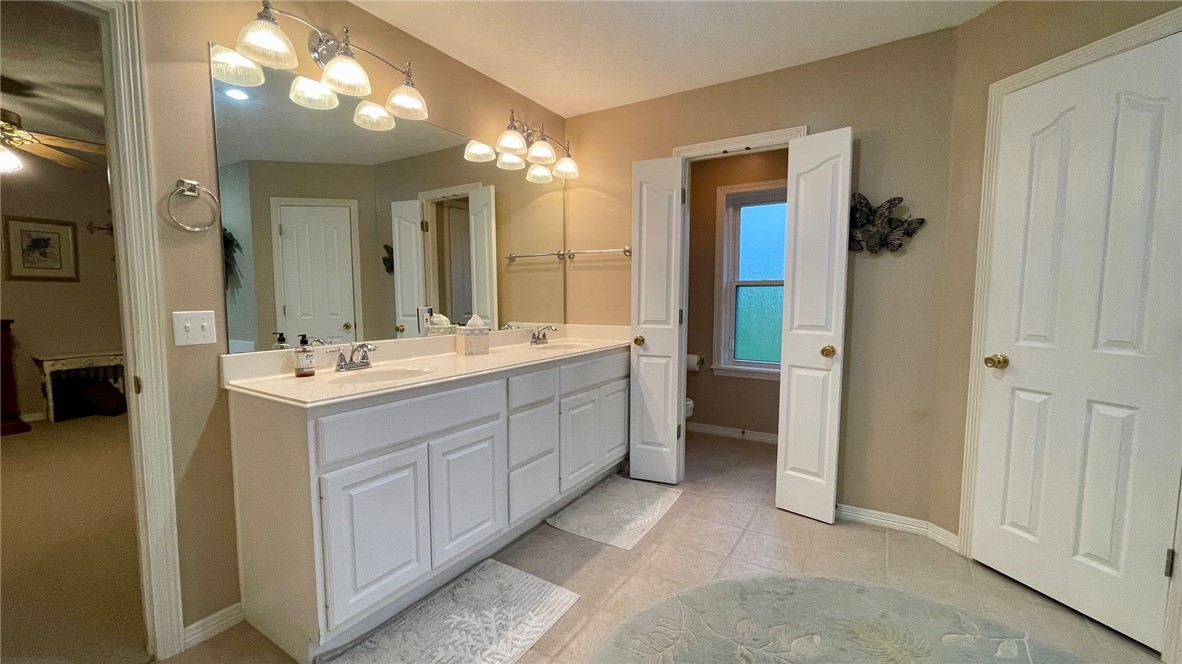 10432 Sammys Road Bremond, TX 76629 - Photo 16 of 47 a bathroom with a double vanity sink a mirror and a shower