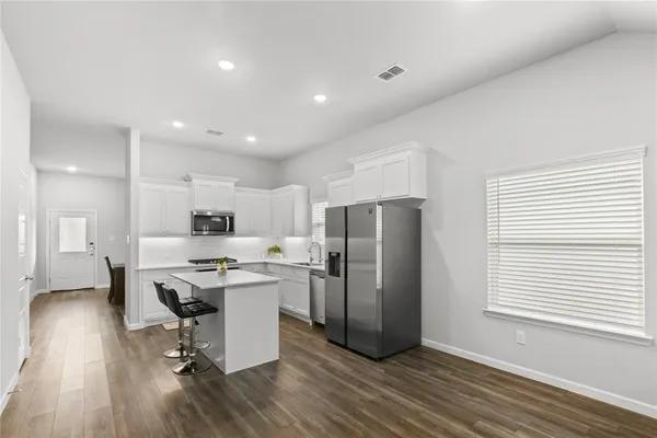 a kitchen with stainless steel appliances a refrigerator a stove a sink dishwasher and a dining table with wooden floor
