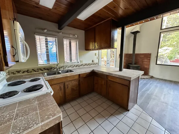 a view of a refrigerator in kitchen and an empty room