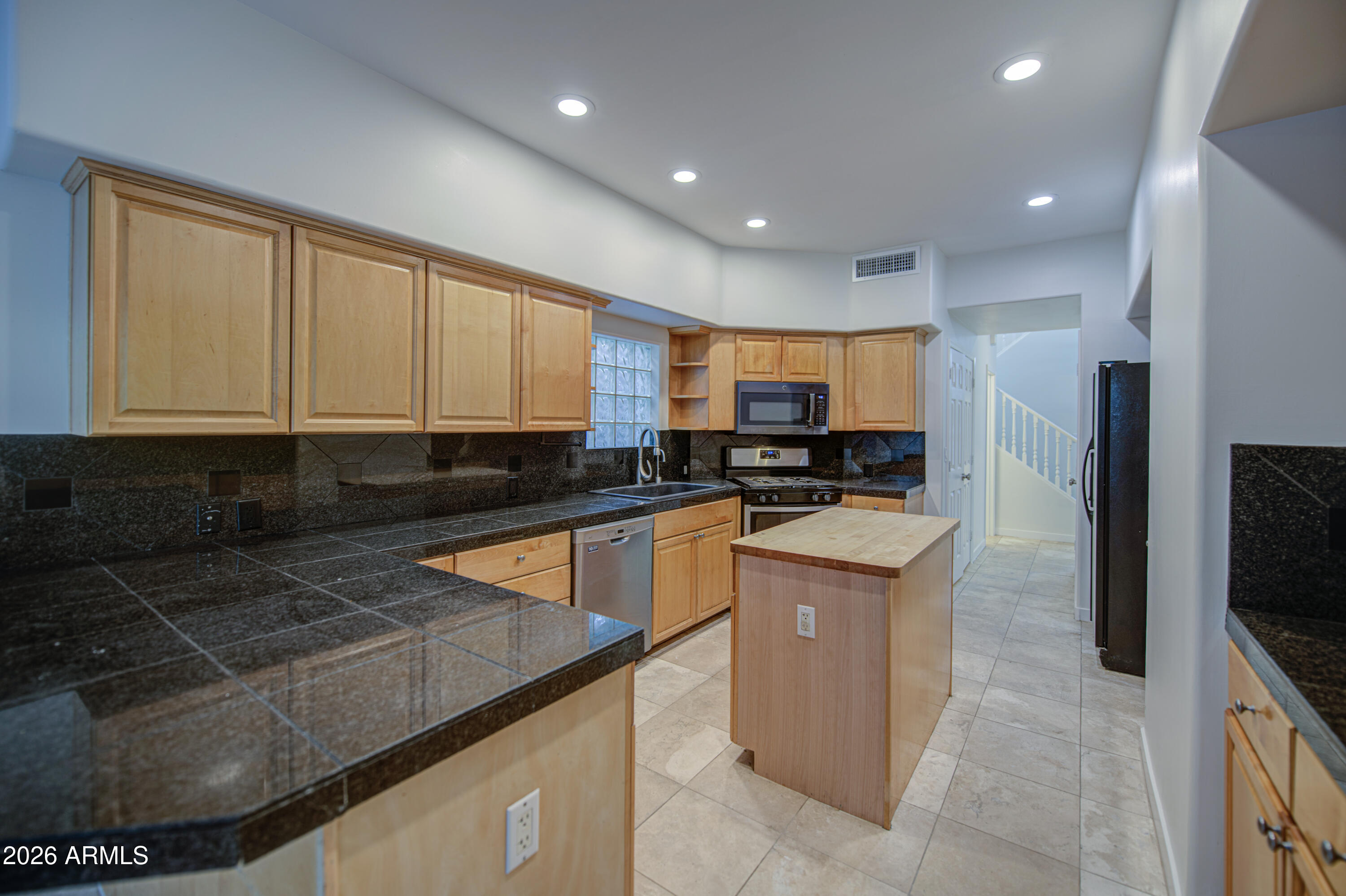 6018 North 5th Place Phoenix, AZ 85014 - Photo 18 of 53 a kitchen with stainless steel appliances granite countertop a stove a sink a refrigerator a microwave oven with white cabinets