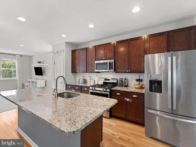 a kitchen with kitchen island granite countertop a sink refrigerator and cabinets