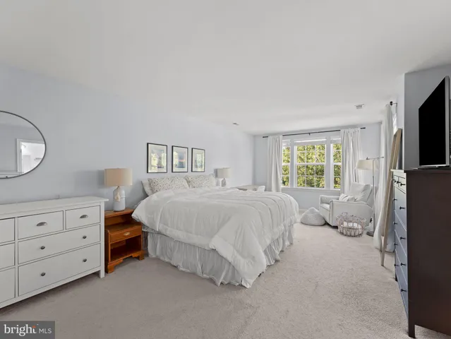 a bedroom with a bed and a flat tv screen on dresser