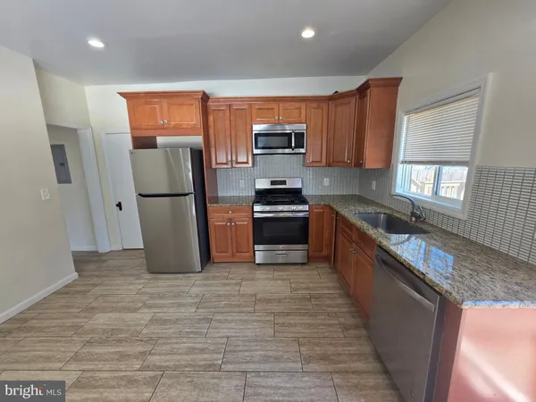 a kitchen with stainless steel appliances granite countertop a refrigerator a sink a stove top oven and a dishwasher next to a window