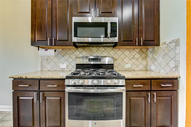 a kitchen with granite countertop a stove top oven microwave and cabinets