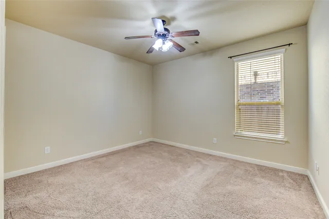 an empty room with chandelier fan and windows